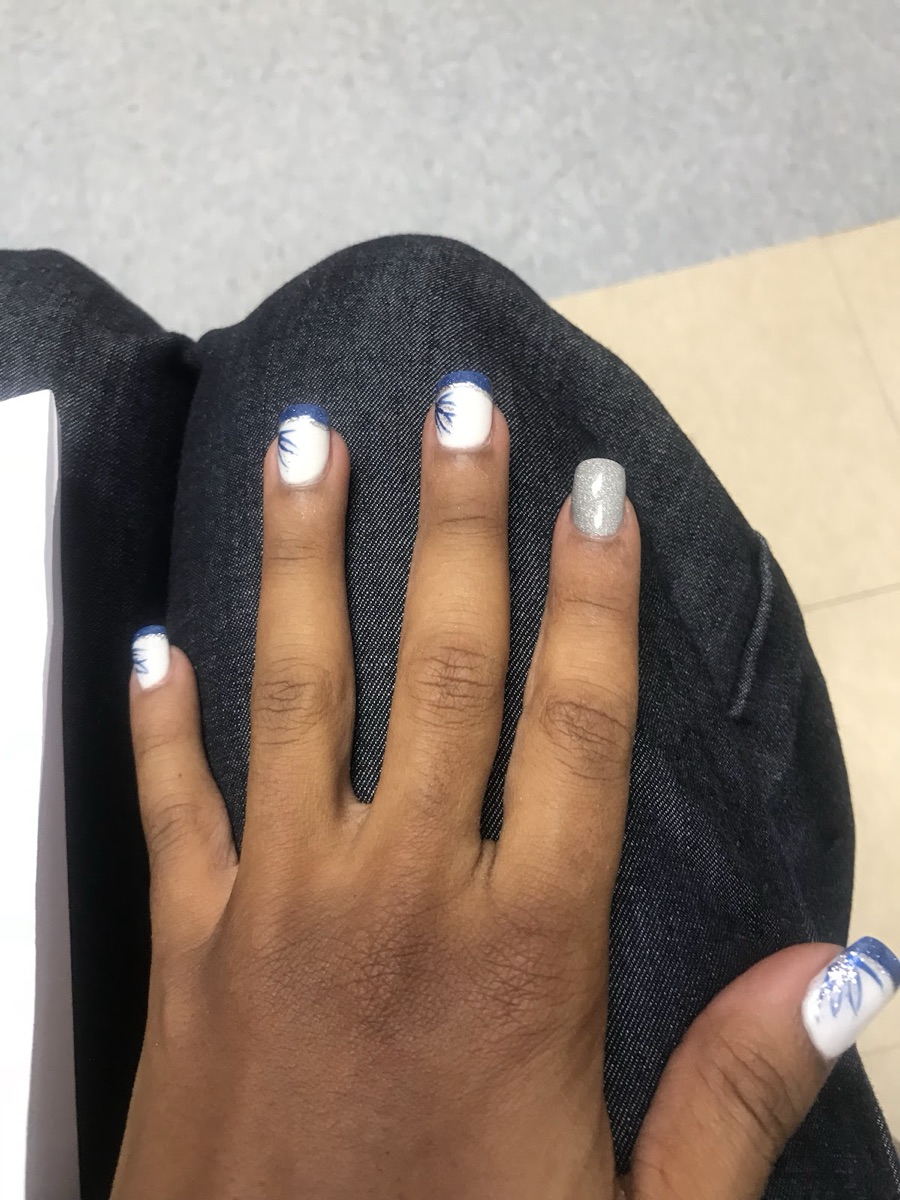 White nails with hand-painted navy floral detail and a silver glitter accent